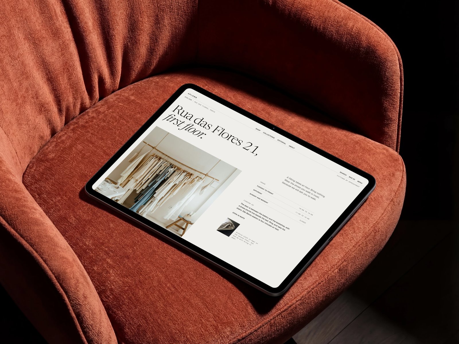 The atelier page on a tablet set on a rust armchair, headed Rua das Flores 21, first floor, beside a photograph of a clothes rail