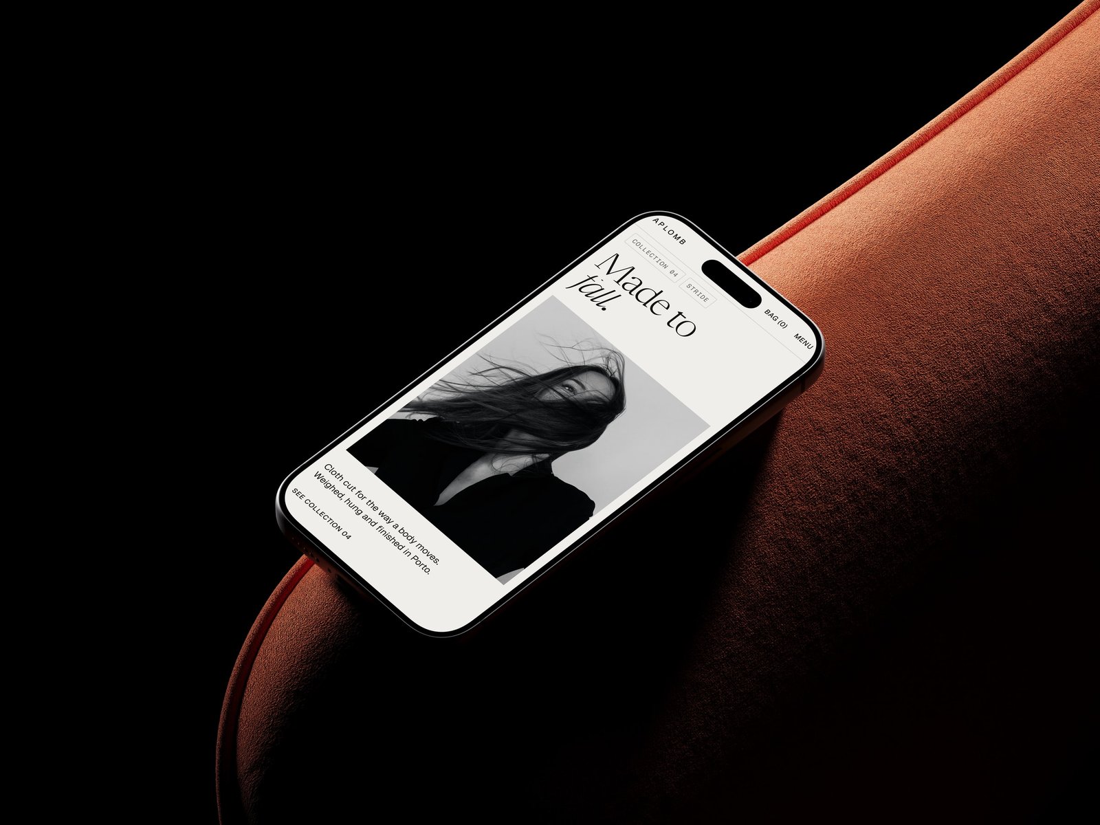 The Aplomb home page on a phone resting on the arm of a rust sofa, the same Made to fall statement over the campaign image